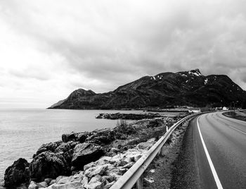 Scenic view of sea by mountain against sky