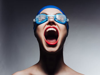 Portrait of young woman wearing mask against black background