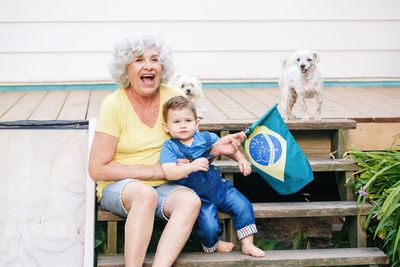 Senior woman holding flag sitting with son on steps