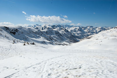 Scenic view of snow covered mountains against cloudy sky