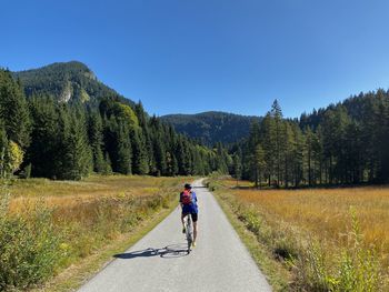 Man riding bicycle on road against clear sky