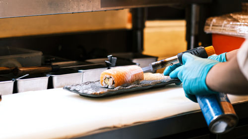 Flame from torch burning salmon in commercial kitchen