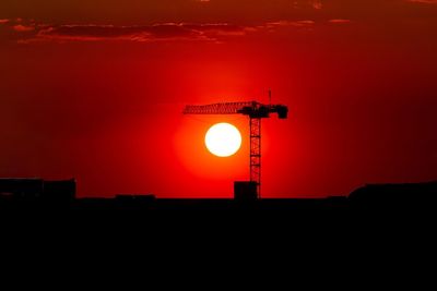 Silhouette built structure against orange sky