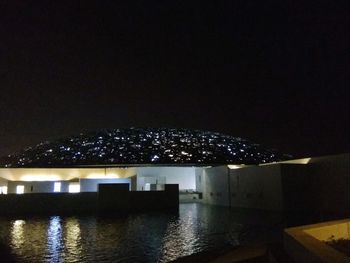 Illuminated buildings against clear sky at night