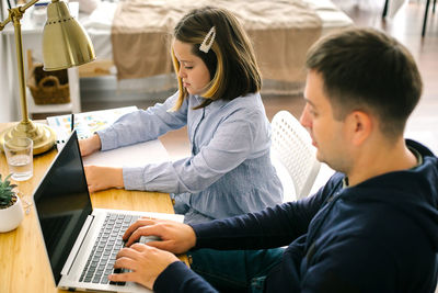 Side view of young woman using laptop at home