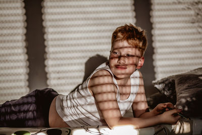 Sunlight falling on thoughtful boy lying on bed