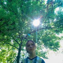 Low angle portrait of woman standing against trees