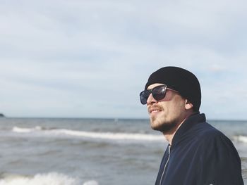 Man in sunglasses at beach against sky