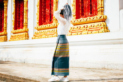 Rear view of woman standing at temple against building