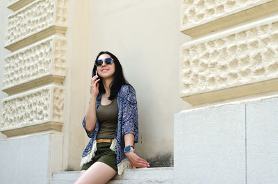 Young woman standing against wall