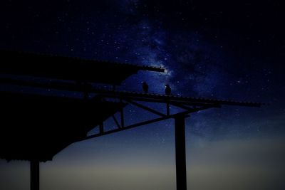 Low angle view of silhouette built structure against sky at night