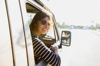 Portrait of happy woman in mini van on road