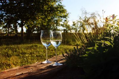 Close-up of wineglass on table against sky at sunset