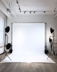 White backdrop with lighting equipment on floor at studio