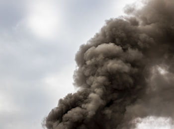 Low angle view of smoke emitting from chimney against sky