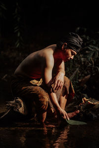 Side view of man sitting in lake