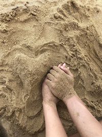 Cropped image of hands on sand