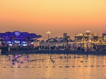 Illuminated pier over sea against sky at sunset