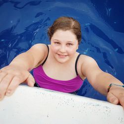 High angle portrait of smiling overweight girl in swimming pool