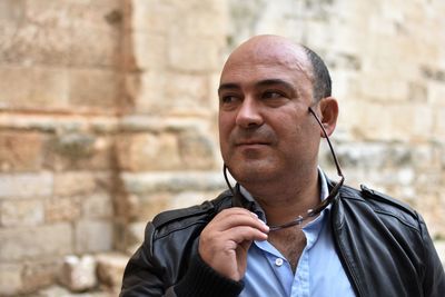 Close-up of mature man looking away while standing against wall