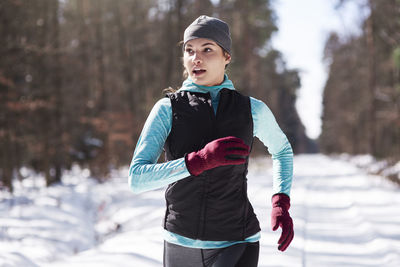 Portrait of young woman jogging in winter forest