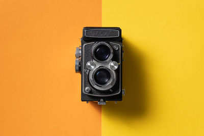 Retro analogue camera. vintage old fashioned camera with lens on two colored background. top view.