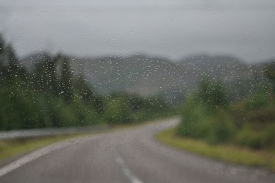 Road seen through wet window in rainy season