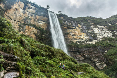 Low angle view of waterfall on rocks against sky