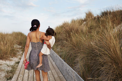 Rear view of woman carrying daughter