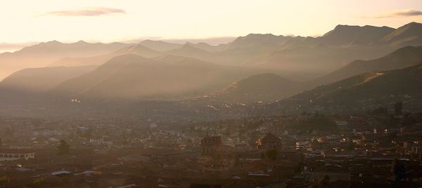 Aerial view of illuminated mountains against sky at sunset