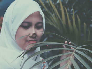 Close-up of young woman in hijab by plant