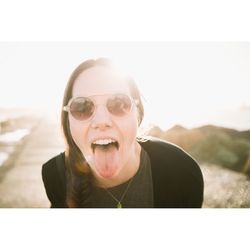 Portrait of young woman wearing sunglasses against clear sky