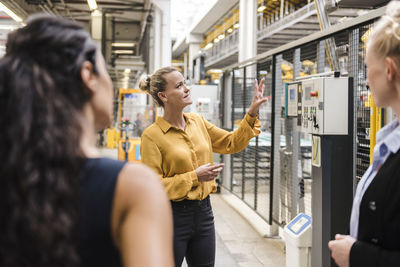 Woman explaining machine to colleagues in modern factory