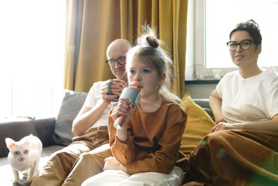 Girl singing song while sitting with parents at home