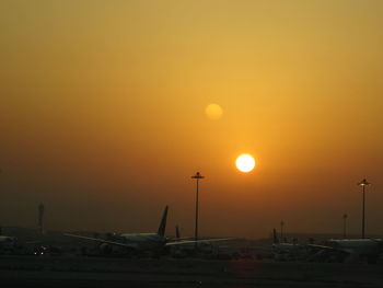 Airplane at airport against sky during sunset