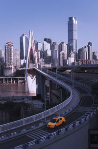 Bridge over river by buildings in city against clear sky