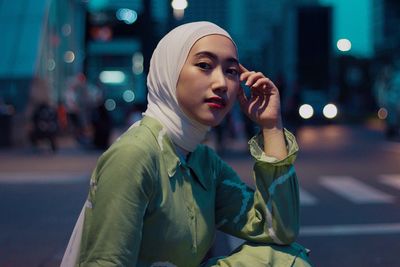 Portrait of young woman looking away on street in city