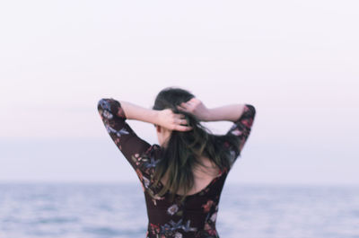 Woman standing by sea against clear sky