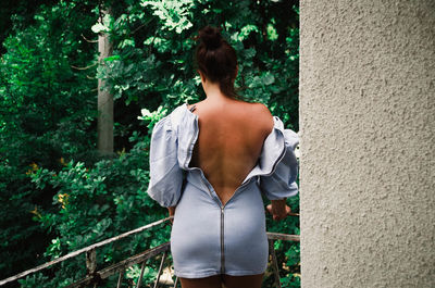 Rear view of woman standing by tree against plants