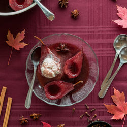 Top down view of red wine poached pears topped with vanilla ice cream.