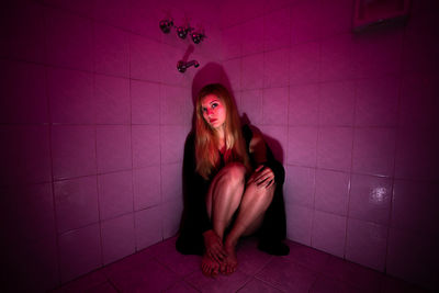 Portrait of young woman sitting on wall at home