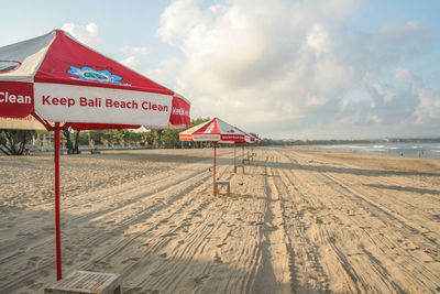 Sign board on beach against sky