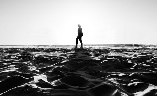 Silhouette man standing in sea against clear sky