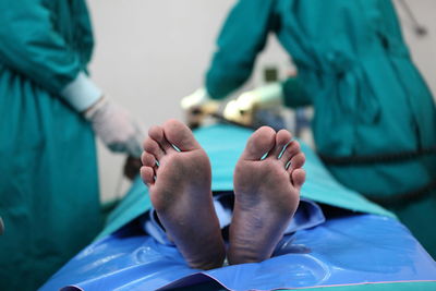 Low section of patient with doctors working in background