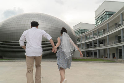 Rear view of people walking against buildings in city