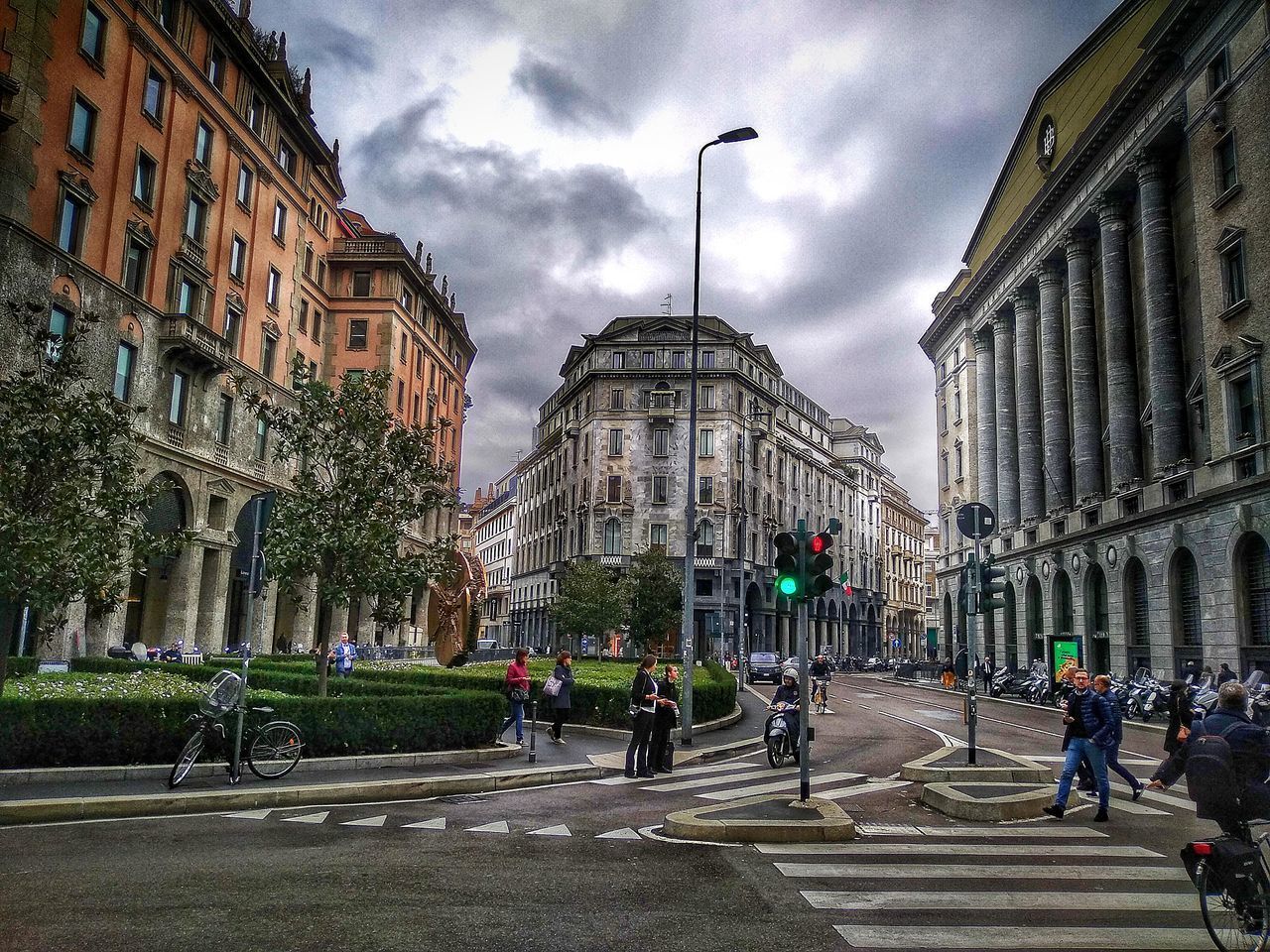 GROUP OF PEOPLE WALKING ON ROAD AGAINST BUILDINGS