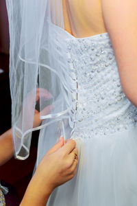 Cropped hands of beautician dressing bride during wedding