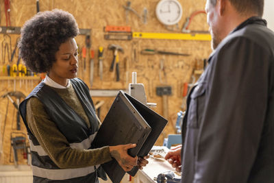 Female technician examining laptop while talking to customer at recycling center