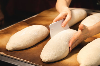 A raw loaf of french bread lies on a wooden board. preparing before baking artisan bread