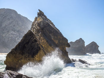 Rock formation in sea against clear sky